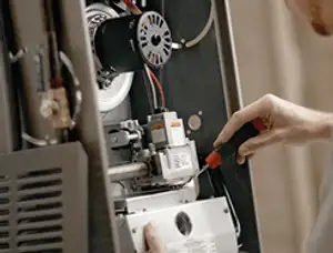 Furnace repair technician inspecting internal components and wiring in Buffalo, NY