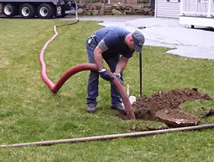 Septic pumping technician servicing a residential septic tank with a vacuum hose in Buffalo, NY