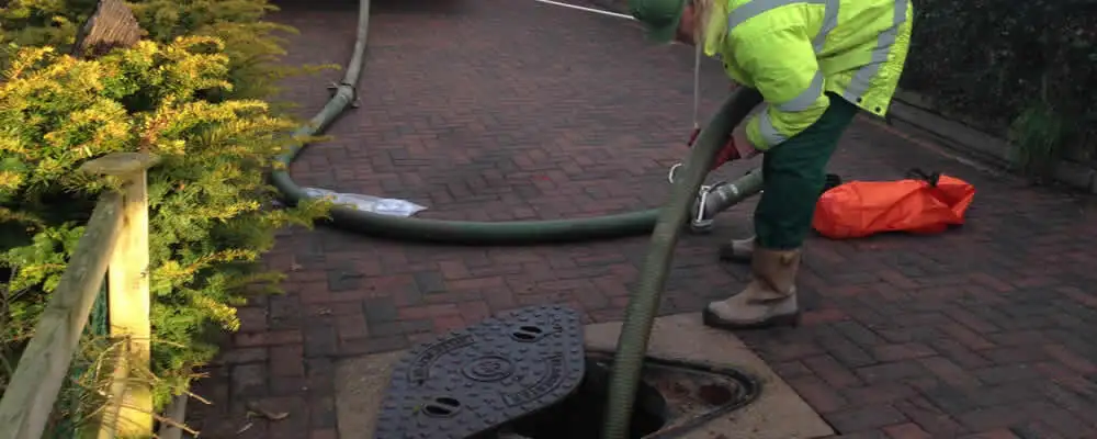 Septic tank cleaning technician servicing a septic tank with a vacuum hose in Buffalo, NY
