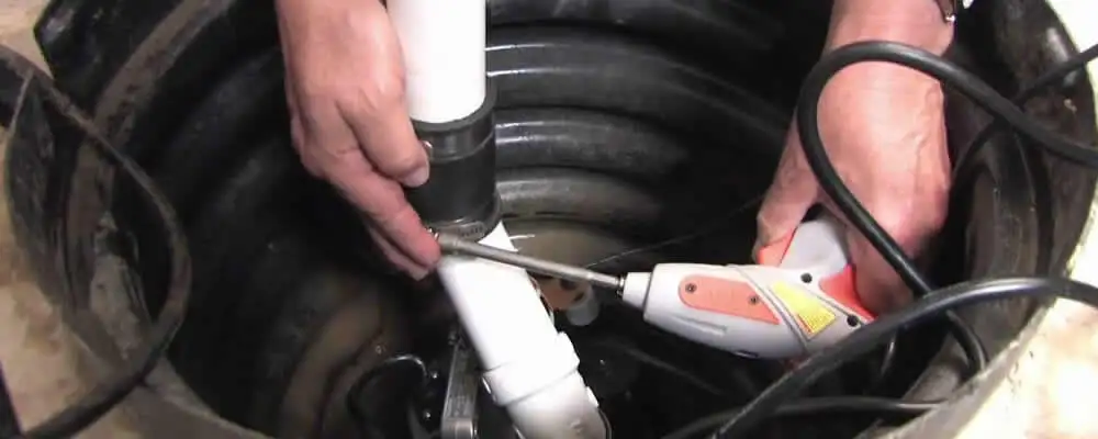 Sump pump installation technician connecting PVC discharge piping in Buffalo, NY