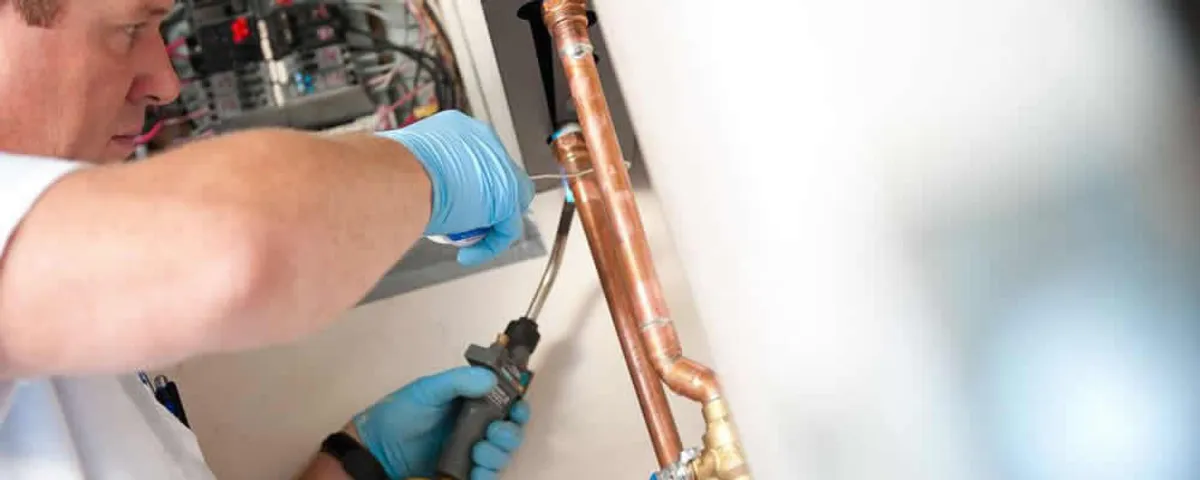 Water heater repair technician testing copper pipe connections and controls in Buffalo, NY