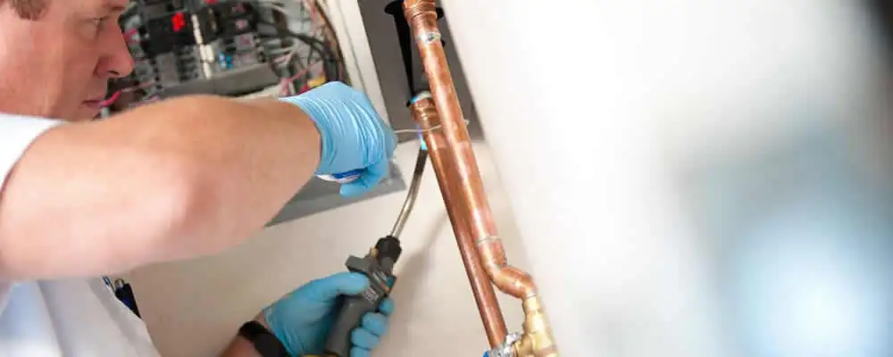 Water heater repair technician testing copper pipe connections and controls in Buffalo, NY